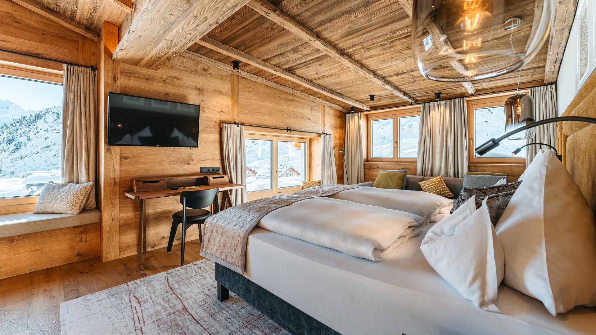 Zum Pressebereich des Hotel Maiensee Gemütliches Schlafzimmer in Holz mit Ausblick auf verschneite Berge