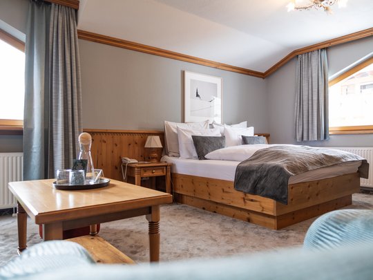Your hotel in St. Christoph am Arlberg Cozy hotel room with wooden furniture, large bed, and a table