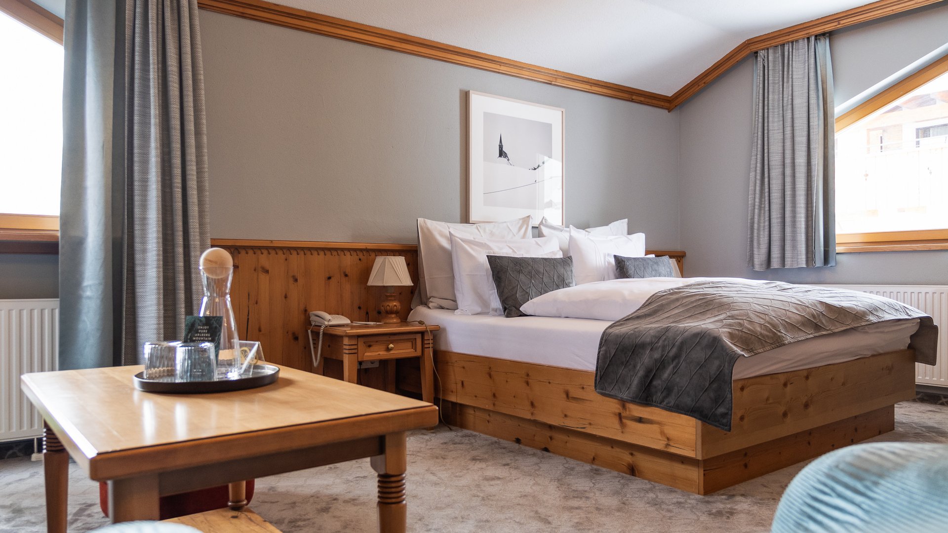 Buchen Sie Ihren Urlaub im Maiensee, Ihrem Hotel am Arlberg Gemütliches Hotelzimmer mit Holzmöbeln, großem Bett und Tisch