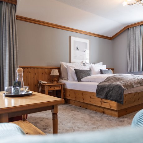 Ihre Unterkunft in St. Christoph am Arlberg: Bilder Gemütliches Hotelzimmer mit Holzmöbeln, großem Bett und Tisch