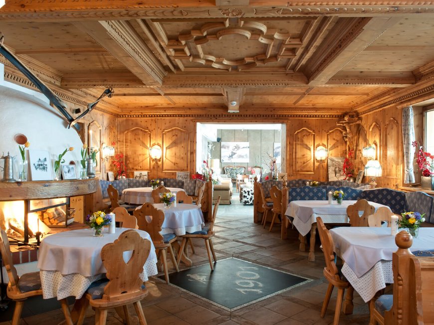 Genuss pur im 4-Sterne-Hotel in St. Anton Gemütlicher Holzesstischraum mit Kamin und dekorierten Tischen
