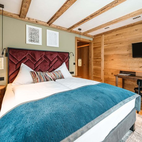 Ihre Unterkunft in St. Christoph am Arlberg: Bilder Modernes Schlafzimmer mit Holzdecke, Doppelbett und Fernseher an der Wand