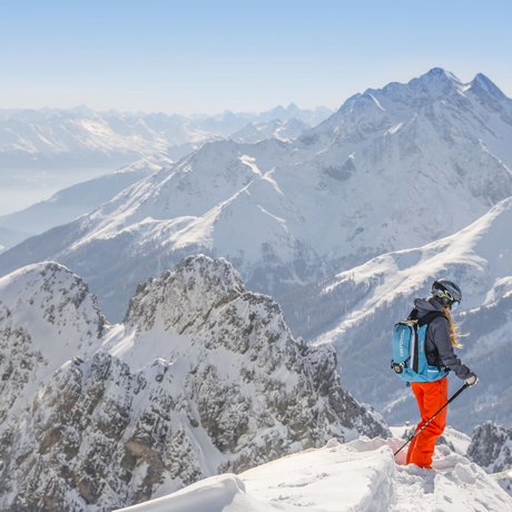 Ihre Unterkunft in St. Christoph am Arlberg: Bilder Skifahrer mit blauem Rucksack auf verschneitem Berggipfel mit Alpenpanorama