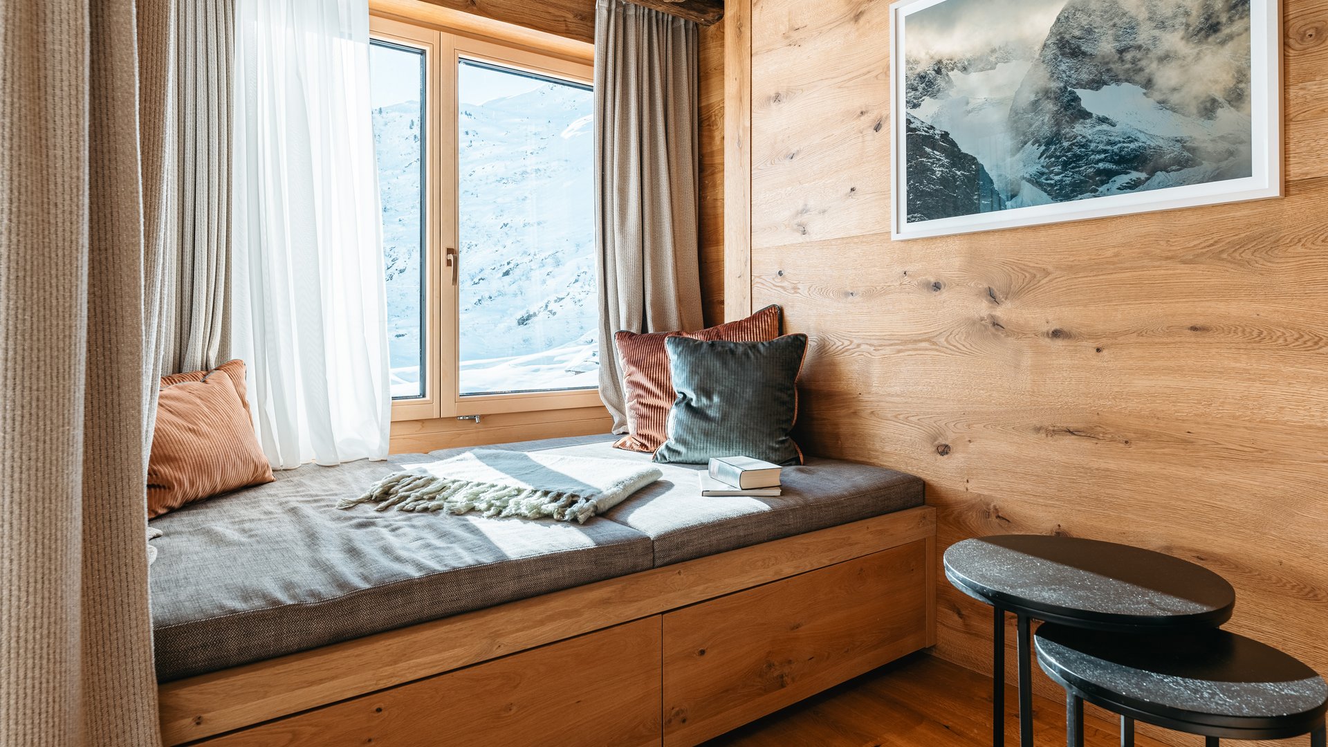 Zum Pressebereich des Hotel Maiensee Gemütlicher Fensterplatz mit Kissen, Decke und Bergblick durch das Fenster