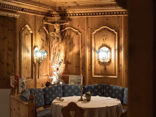 Your hotel in St. Christoph am Arlberg Cozy wooden corner with round table and blue upholstered bench in traditional style
