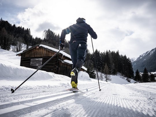 Hotel Maiensee: winter sports at the Arlberg Cross-country skier on snowy trail near wooden cabin and pine forest