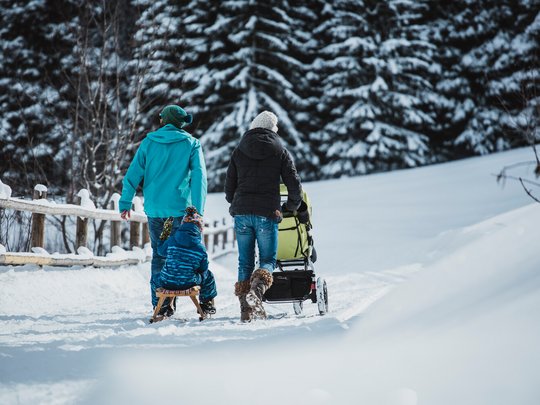Hotel Maiensee: winter sports at the Arlberg Family walking in snow, child sitting on sled