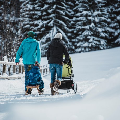 Ihre Unterkunft in St. Christoph am Arlberg: Bilder Familie geht im Schnee spazieren, Kind sitzt auf Schlitten