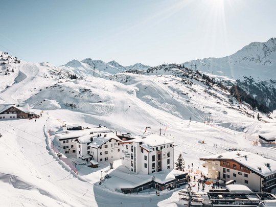 The lounge bar in your ski hotel at the Arlberg Snow-covered mountain landscape with hotels and skiers on a sunny winter day