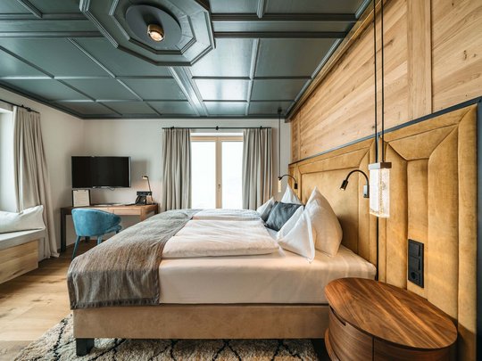 Your hotel in St. Christoph am Arlberg Modern hotel room with large bed, wooden accents, and television