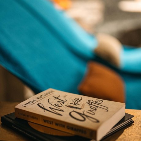 Ihre Unterkunft in St. Christoph am Arlberg: Bilder Buch West with Giraffes auf einem Tisch vor einem blauen Stuhl