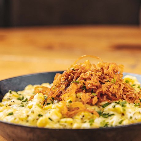 Ihre Unterkunft in St. Christoph am Arlberg: Bilder Käsespätzle mit Röstzwiebeln in einer schwarzen Pfanne serviert