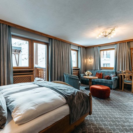 Ihre Unterkunft in St. Christoph am Arlberg: Bilder Gemütliches Hotelzimmer mit Bett, Sofa und Bergblick durch Fenster