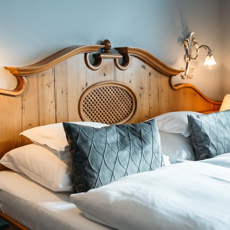 Ihre Unterkunft in St. Christoph am Arlberg: Bilder Gemütliches Doppelbett mit Holz-Kopfteil und blauen Kissen