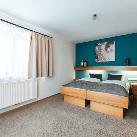 Ihre Unterkunft in St. Christoph am Arlberg: Bilder Gemütliches Schlafzimmer mit Holzmöbeln und blauem Akzentwand