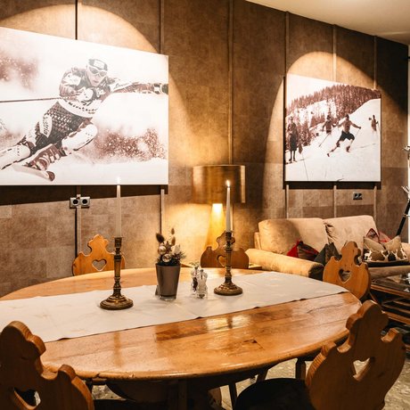 Ihre Unterkunft in St. Christoph am Arlberg: Bilder Gemütlicher Essbereich mit Holztisch und Skifahrerfotografien an der Wand