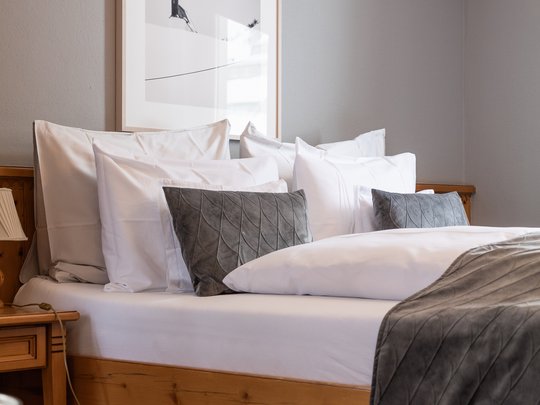 Hotel Maiensee: your hotel in St. Christoph Cozy double bed with many pillows and gray blanket in a bright room