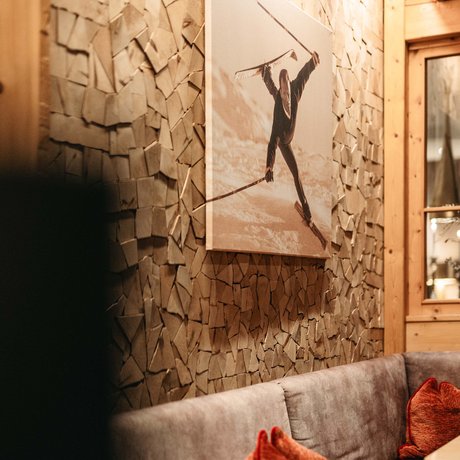 Ihre Unterkunft in St. Christoph am Arlberg: Bilder Gemütliche Sitzecke mit vintage Skifahrer-Foto und Holzstapel-Wand im Skihüttenstil