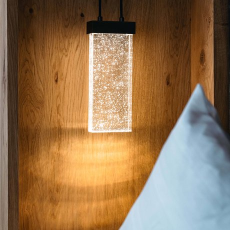 Ihre Unterkunft in St. Christoph am Arlberg: Bilder Moderne Hängelampe mit Glaskörper und Sternenlicht auf Holzwand neben Kissen