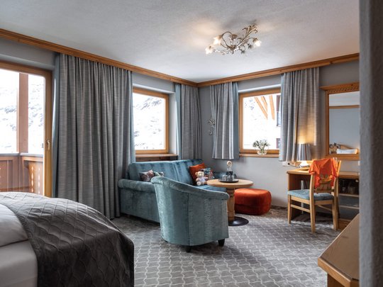 Hotel Maiensee: your hotel in St. Christoph Bright room with sofa, armchairs, desk, and windows with curtains