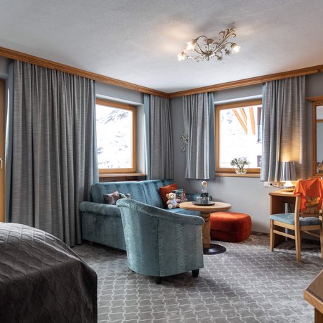 Ihre Unterkunft in St. Christoph am Arlberg: Bilder Helles Zimmer mit Sofa, Sesseln, Schreibtisch und Fenster mit Vorhängen