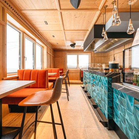 Ihre Unterkunft in St. Christoph am Arlberg: Bilder Innenraum einer modernen Bar mit orangen Sitzbänken und blauer Fliesenbar