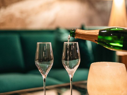 The lounge bar in your ski hotel at the Arlberg Champagne being poured into two glasses in a cozy living room