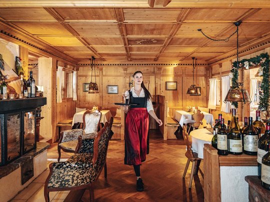 Hotel Maiensee: your hotel in St. Christoph Waitress in traditional dress serving wine in cozy wooden restaurant