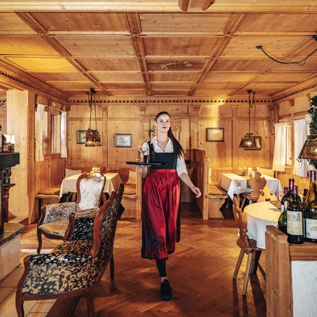 Ihre Unterkunft in St. Christoph am Arlberg: Bilder Kellnerin in traditioneller Kleidung serviert Wein in gemütlichem Holzrestaurant