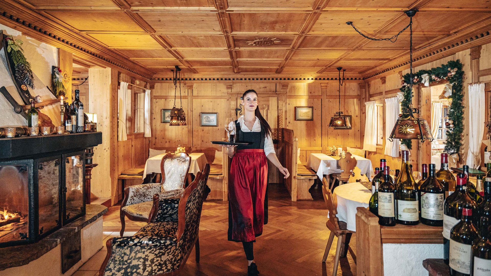 Maiensee, Ihr Hotel in Sankt Christoph: Kulinarik Kellnerin in traditioneller Kleidung serviert Wein in gemütlichem Holzrestaurant