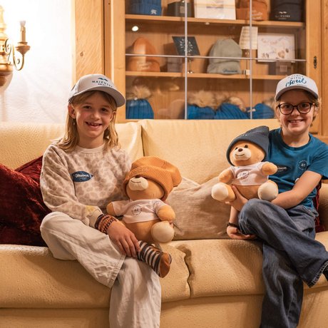Ihre Unterkunft in St. Christoph am Arlberg: Bilder Zwei Kinder sitzen mit Teddy und Mütze auf einem Sofa