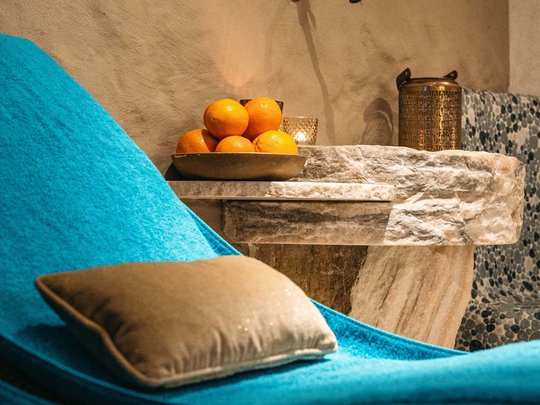 Maiensee: Ihr Wellnesshotel bei St. Anton Blauer Liegestuhl mit Kissen neben Steinbecken und Orangen auf Teller
