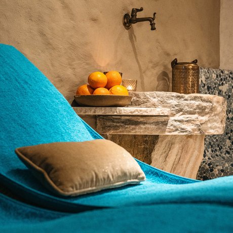 Ihre Unterkunft in St. Christoph am Arlberg: Bilder Blauer Liegestuhl mit Kissen neben Steinbecken und Orangen auf Teller