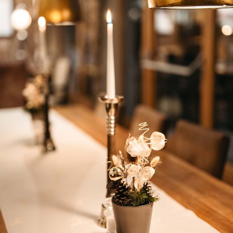 Ihre Unterkunft in St. Christoph am Arlberg: Bilder Kerze und dekorative Blumentöpfe auf einem gedeckten Holztisch