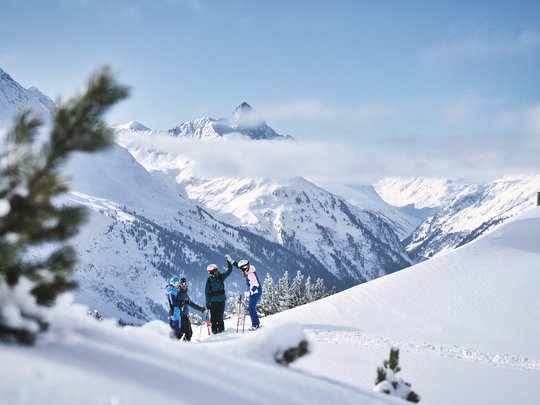 Hotel Maiensee: winter sports at the Arlberg Group of skiers on snowy mountain with Alps and cloudy sky in the background