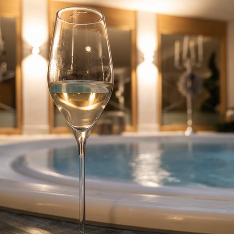 Ihre Unterkunft in St. Christoph am Arlberg: Bilder Weißweinglas vor einem Whirlpool in einem warm beleuchteten Raum
