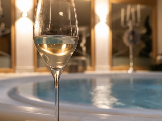 Hotel Maiensee: your hotel in St. Christoph Glass of white wine in front of a hot tub in a warmly lit room