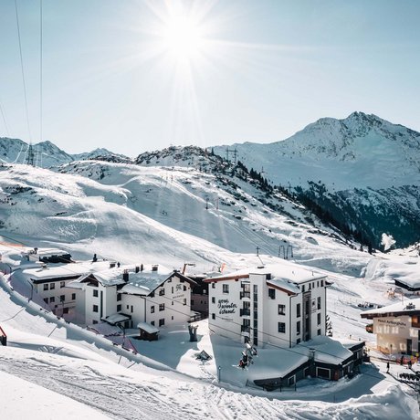 Ihre Unterkunft in St. Christoph am Arlberg: Bilder Schneebedeckte Berglandschaft mit Skigebiet und Gebäuden unter strahlender Sonne