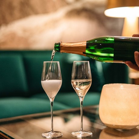 Ihre Unterkunft in St. Christoph am Arlberg: Bilder Sekt wird in zwei Gläser auf einem Glastisch in einer gemütlichen Umgebung eingeschenkt