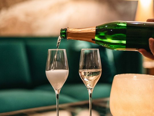 Hotel Maiensee: your hotel in St. Christoph Sparkling wine being poured into two glasses on a glass table in a cozy setting