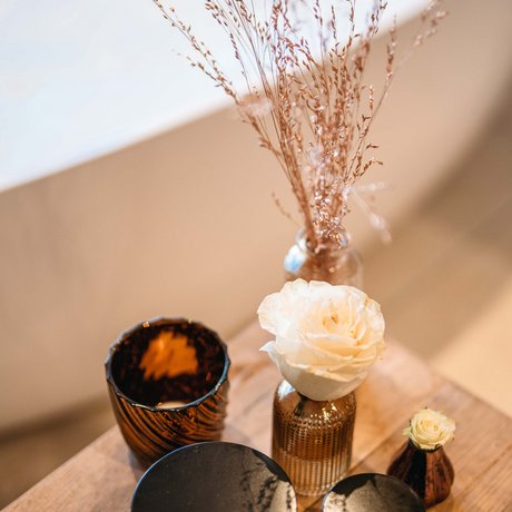 Ihre Unterkunft in St. Christoph am Arlberg: Bilder Zwei schwarze Cremedosen und weiße Rosen in braunen Vasen auf Holztisch