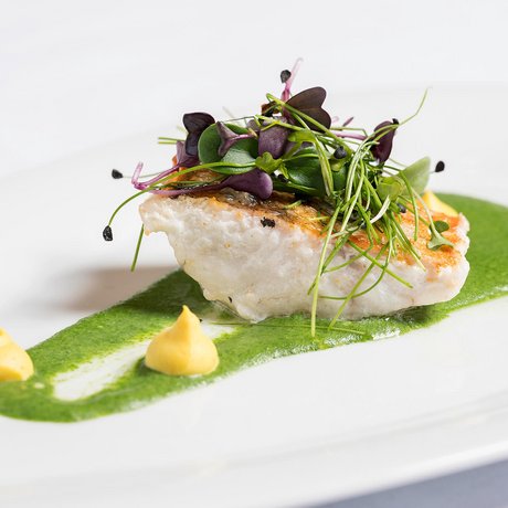 Ihre Unterkunft in St. Christoph am Arlberg: Bilder Gebratenes Fischfilet mit grüner Sauce, Kräutern und zwei kleinen Dips auf weißem Teller