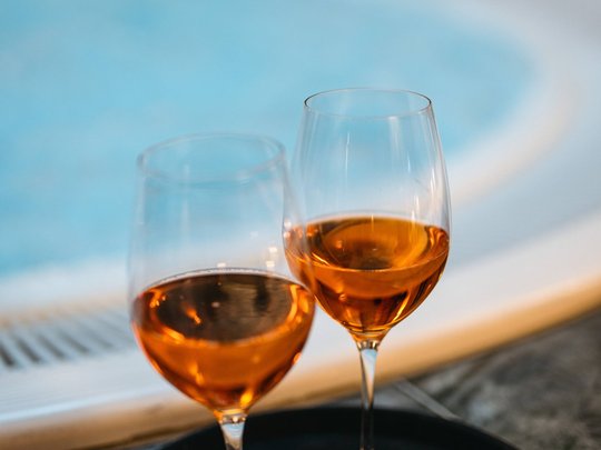 Maiensee: Ihr Wellnesshotel bei St. Anton Zwei Weingläser mit rosé neben einem Pool