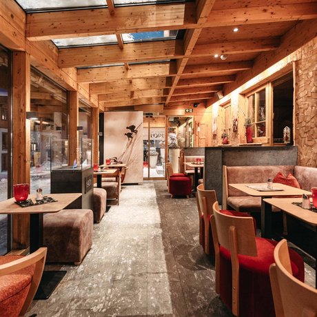 Ihre Unterkunft in St. Christoph am Arlberg: Bilder Gemütliches Café mit Holzmöbeln und großen Fenstern in winterlicher Umgebung