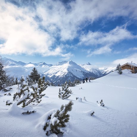 Ihre Unterkunft in St. Christoph am Arlberg: Bilder Schneebedeckte Berge mit Tannen und Hütte unter blauem Himmel