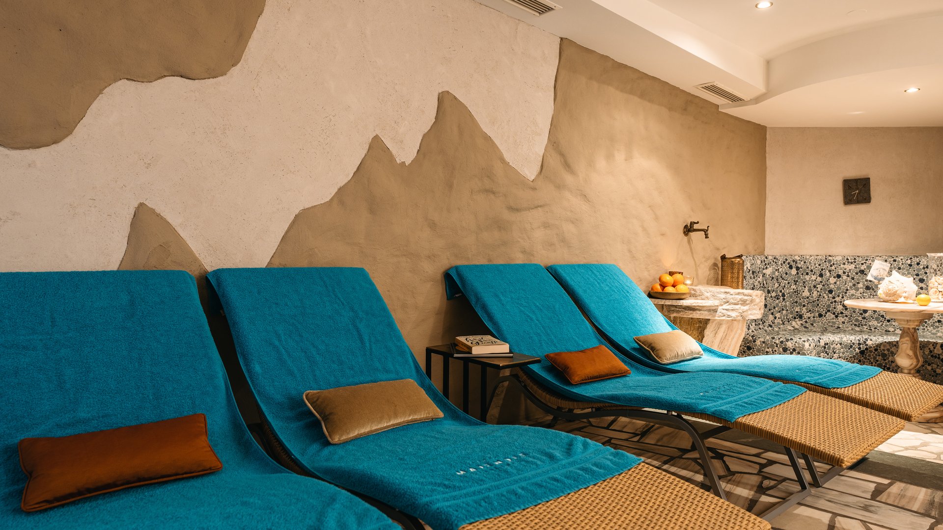 Zum Pressebereich des Hotel Maiensee Ruheraum mit blauen Liegestühlen und dekorativen Kissen in einem Spa