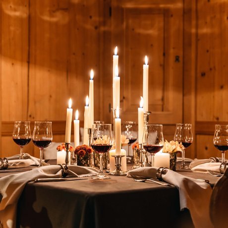Ihre Unterkunft in St. Christoph am Arlberg: Bilder Eleganter gedeckter Tisch mit brennenden Kerzen und Rotweingläsern in Holzzimmer.