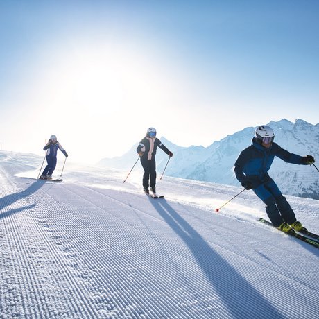 Ihre Unterkunft in St. Christoph am Arlberg: Bilder Drei Skifahrer auf präparierter Piste vor Bergkulisse bei Sonnenschein