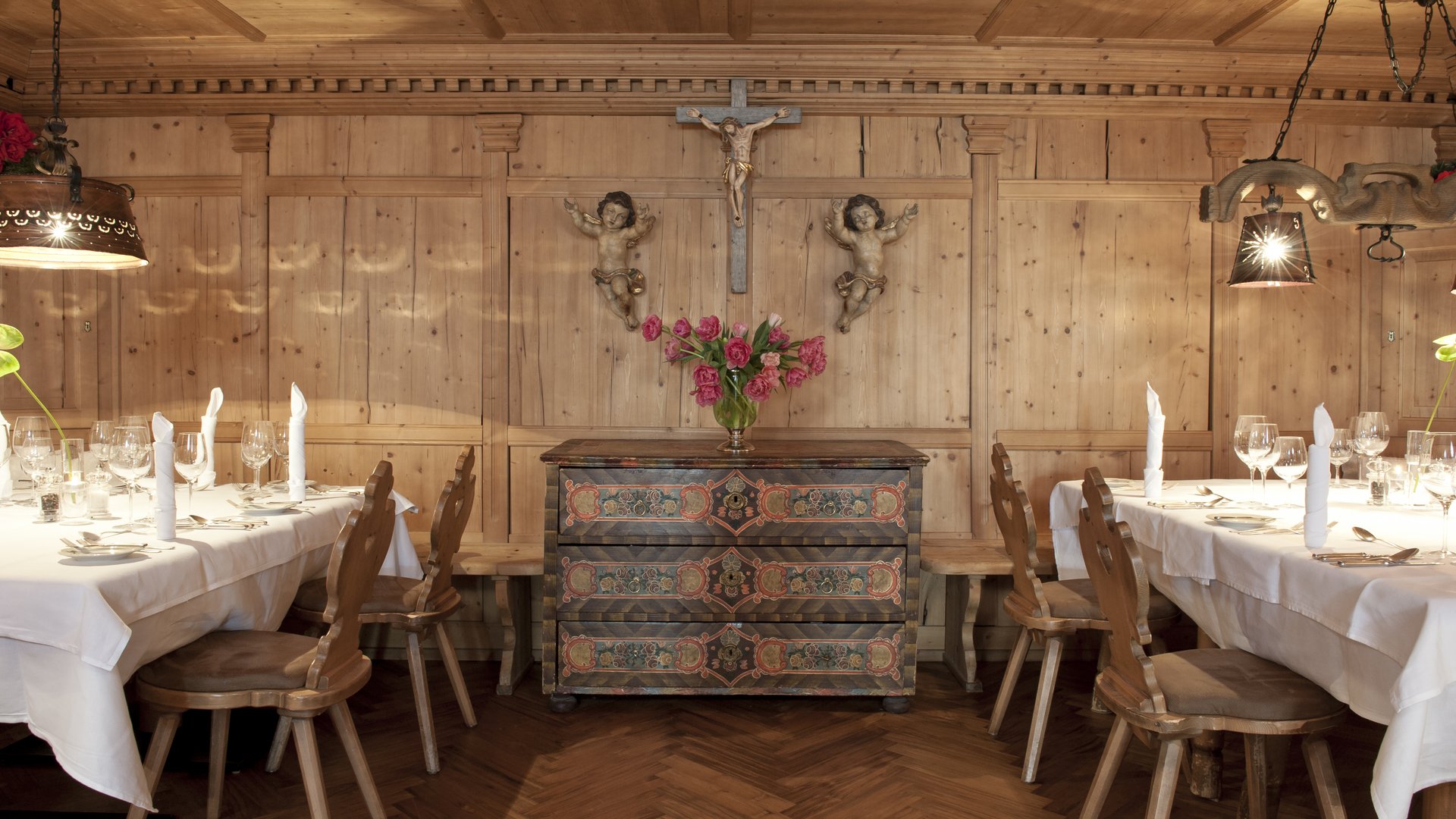 Zum Pressebereich des Hotel Maiensee Rustikales Esszimmer mit Holzmöbeln und religiösen Figuren an der Wand