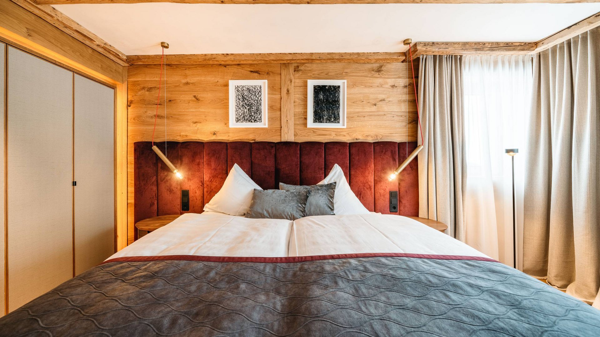 Book your holiday at Maiensee, your hotel at the Arlberg Cozy bedroom with wooden ceiling, red headboard, and modern lighting